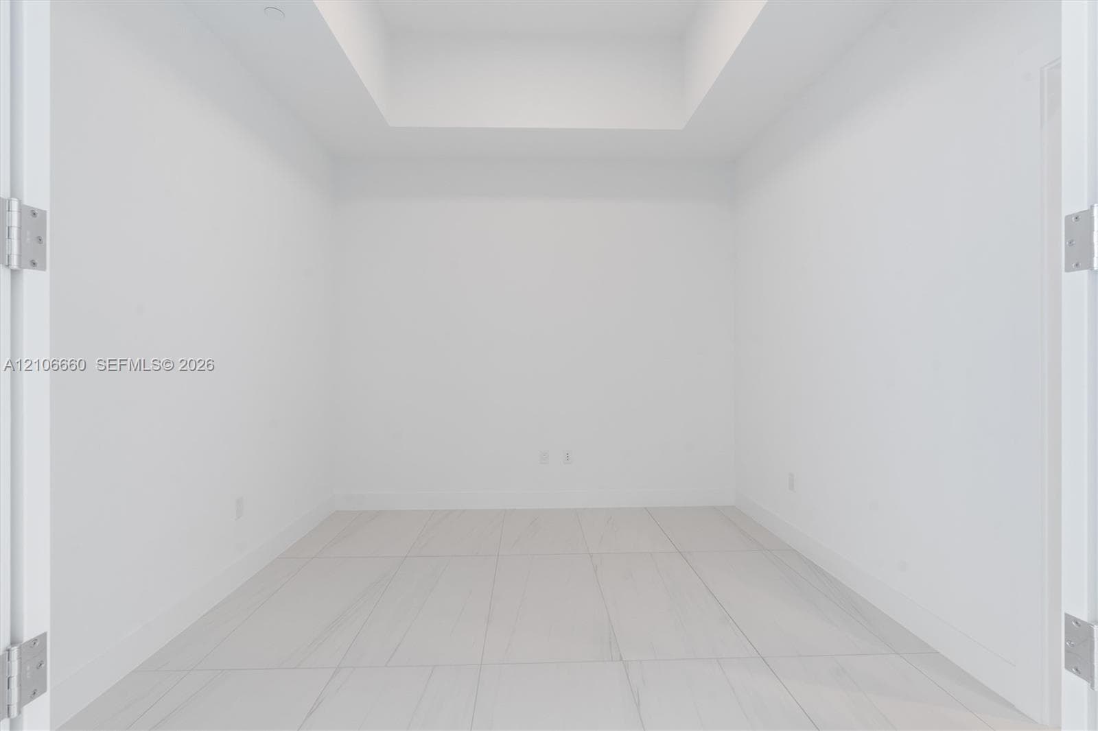 Interior space featuring a recessed ceiling, white walls, and large-format tile flooring