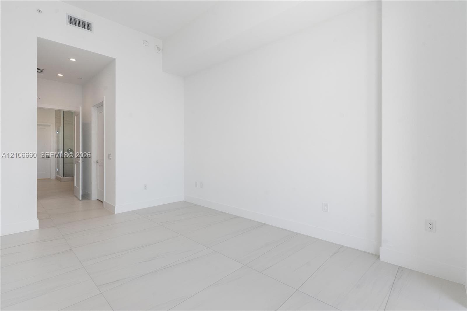High-ceiling interior featuring smooth white walls, large-format tile flooring with marble-style veining, recessed lighting, and solid-core interior doors