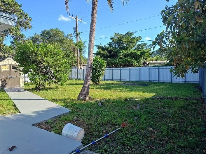 Backyard featuring a concrete walkway, storage shed, and perimeter fencing