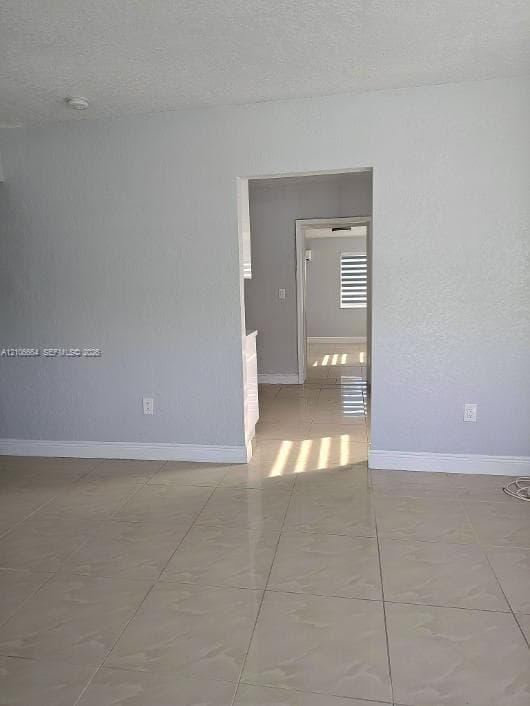 Neutral-toned ceramic tile flooring, textured wall surfaces, and horizontal window blinds