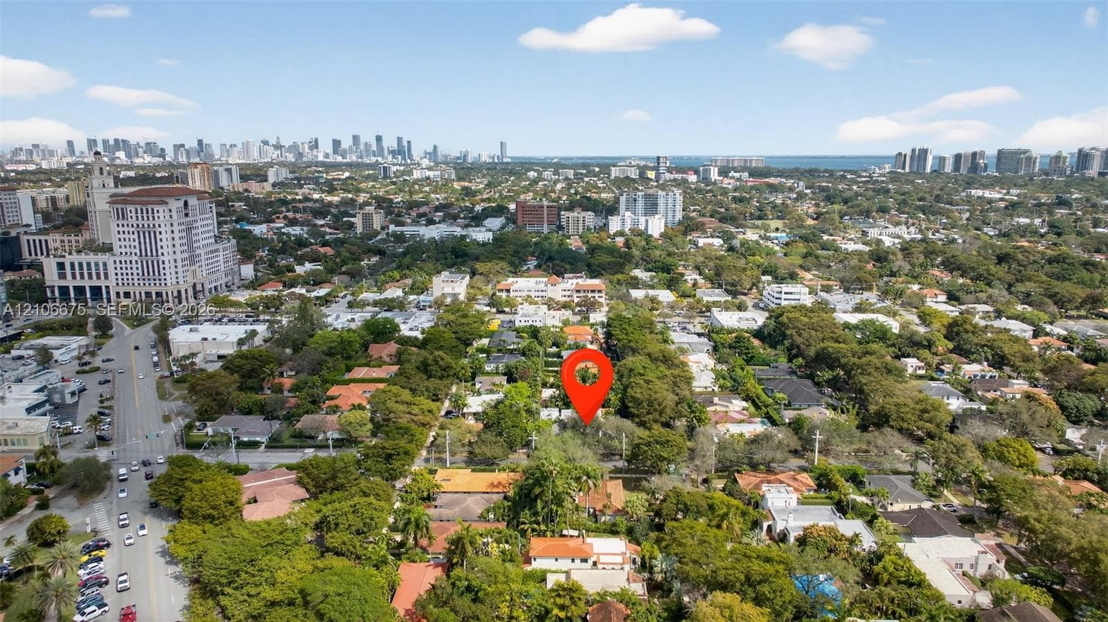 Aerial perspective of a property nestled within a mature, tree-lined residential canopy, featuring proximity to urban infrastructure and a coastal city skyline