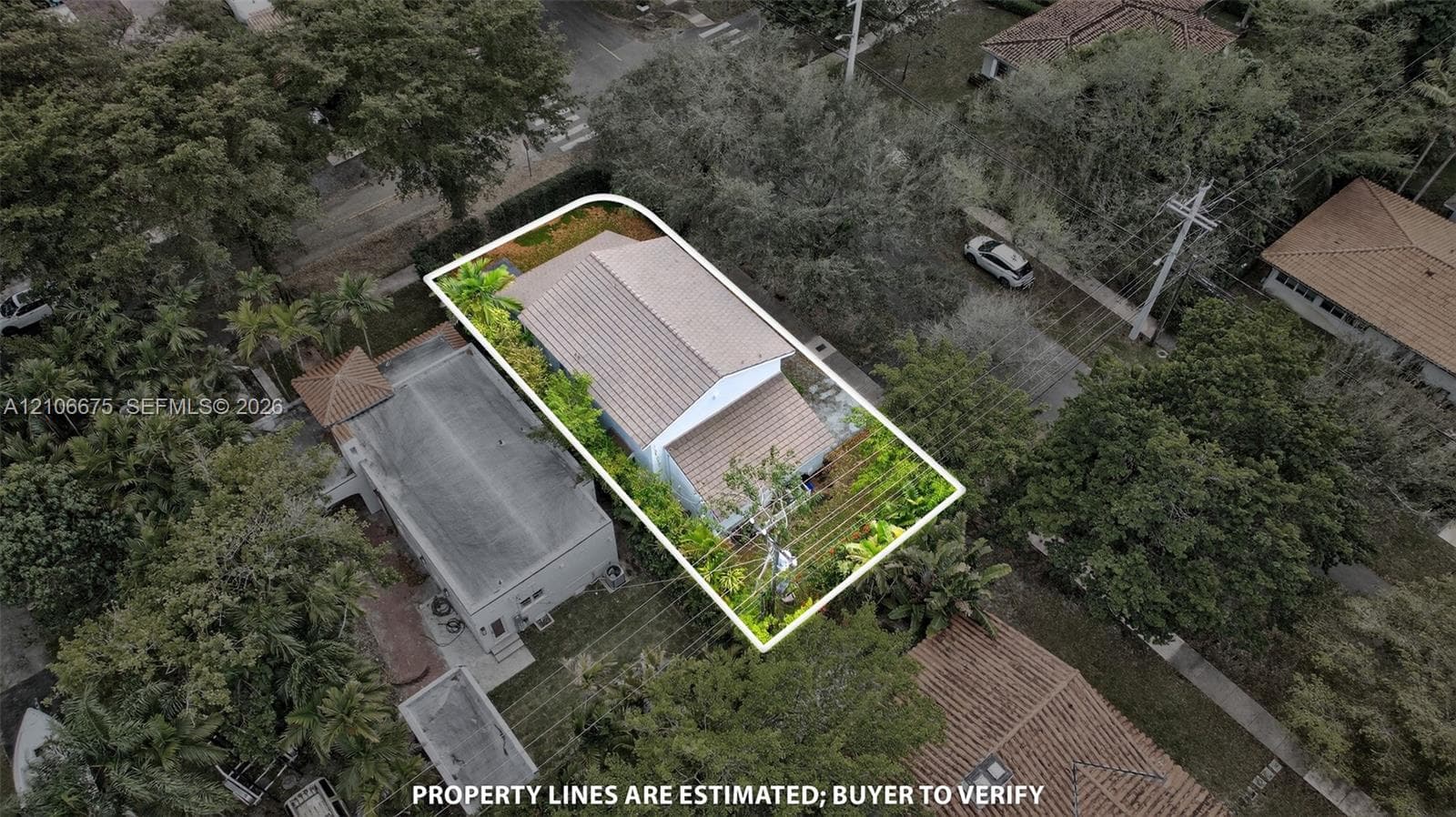 Aerial perspective of a property featuring a pitched tile roof, substantial mature landscaping, and a fenced lot