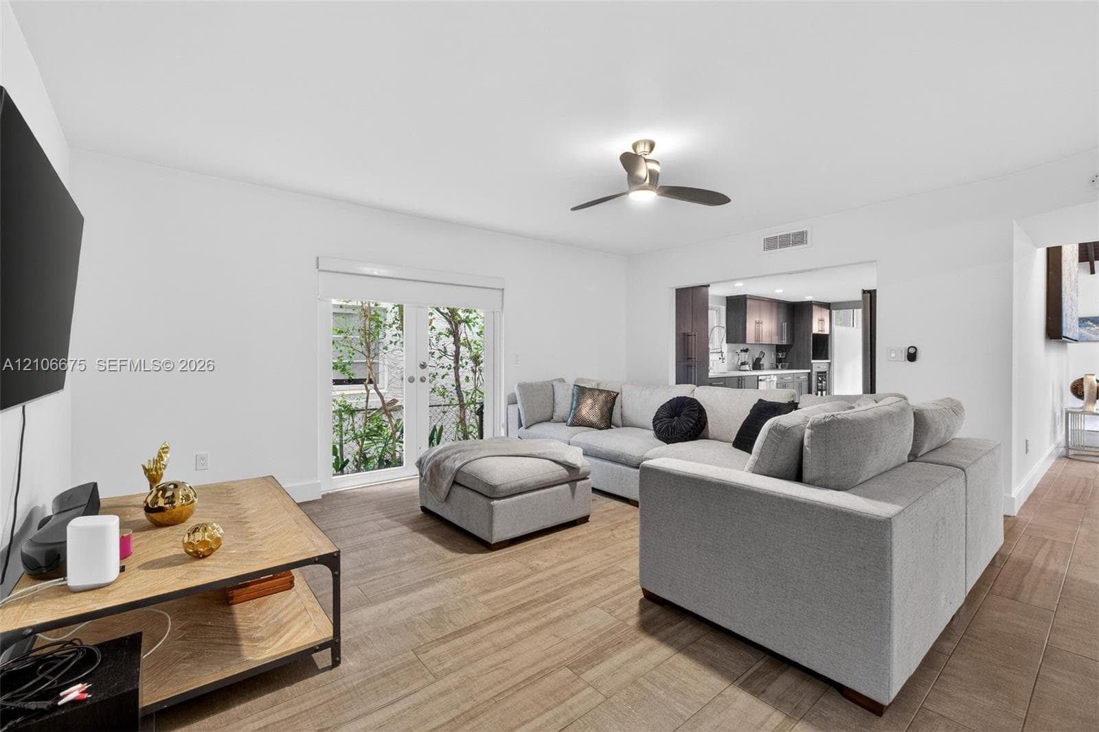 Interior space featuring wood-finish flooring, white walls, and a ceiling fan with integrated lighting