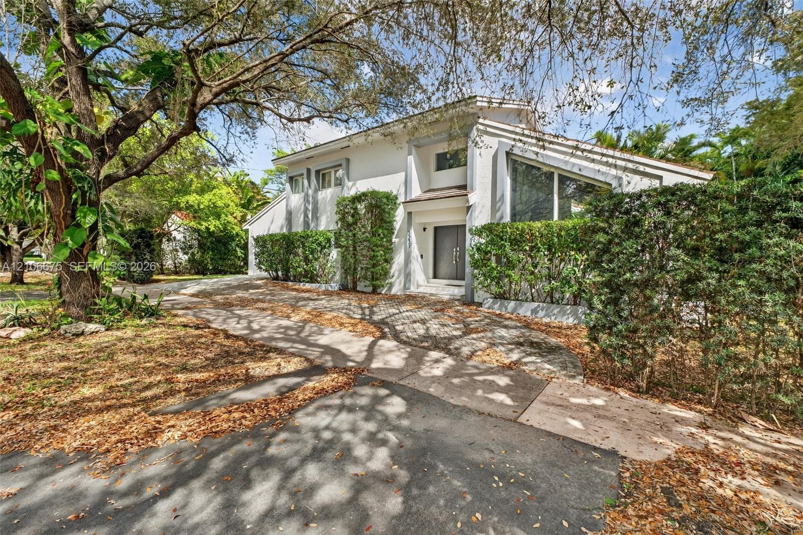 Two-story exterior featuring a stucco facade, angular roofline, multi-pane windows, and a paved driveway