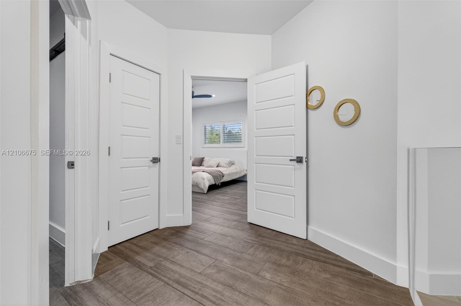 Hallway featuring wood-finish tile flooring, four-panel interior doors, and matte black hardware