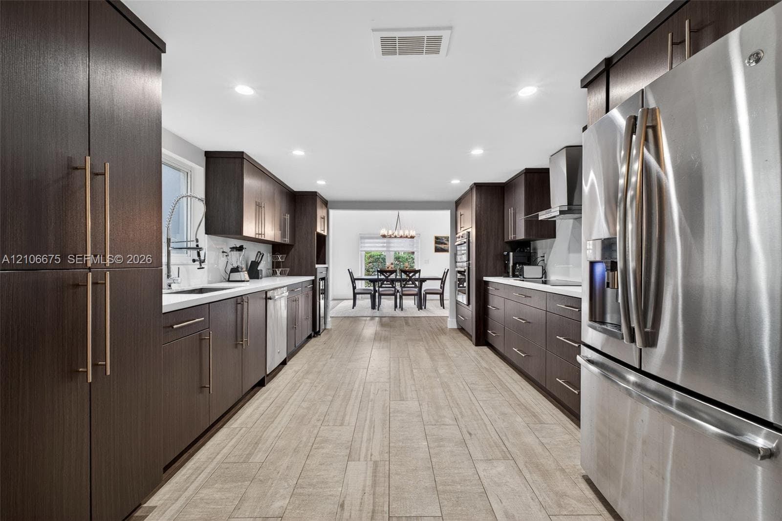 Kitchen featuring dark wood-finish cabinetry, stainless steel appliances, recessed lighting, and wood-finish tile flooring