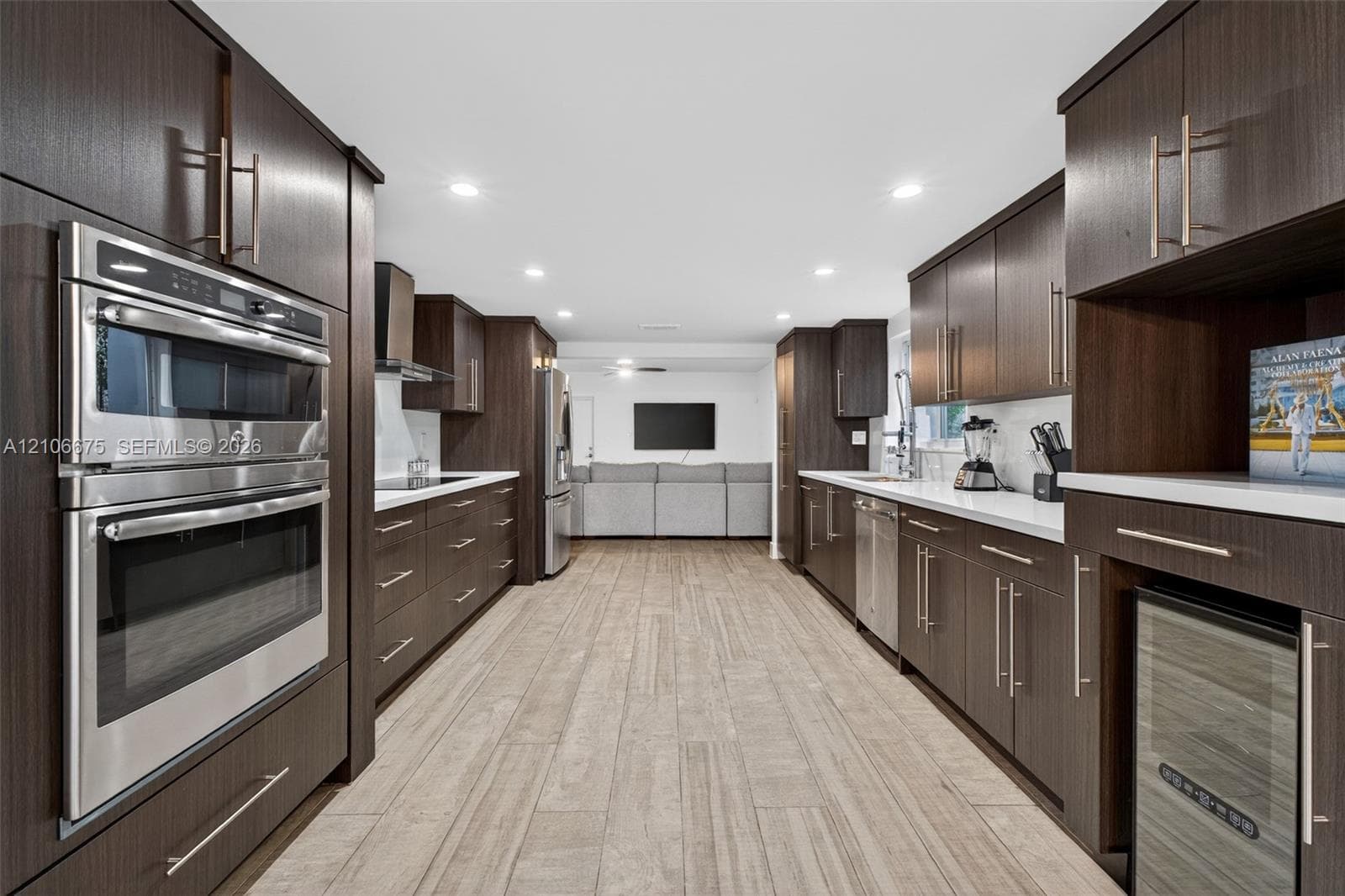 Kitchen featuring dark wood-finish cabinetry, solid-surface countertops, built-in double ovens, stainless steel appliances, and wood-finish flooring
