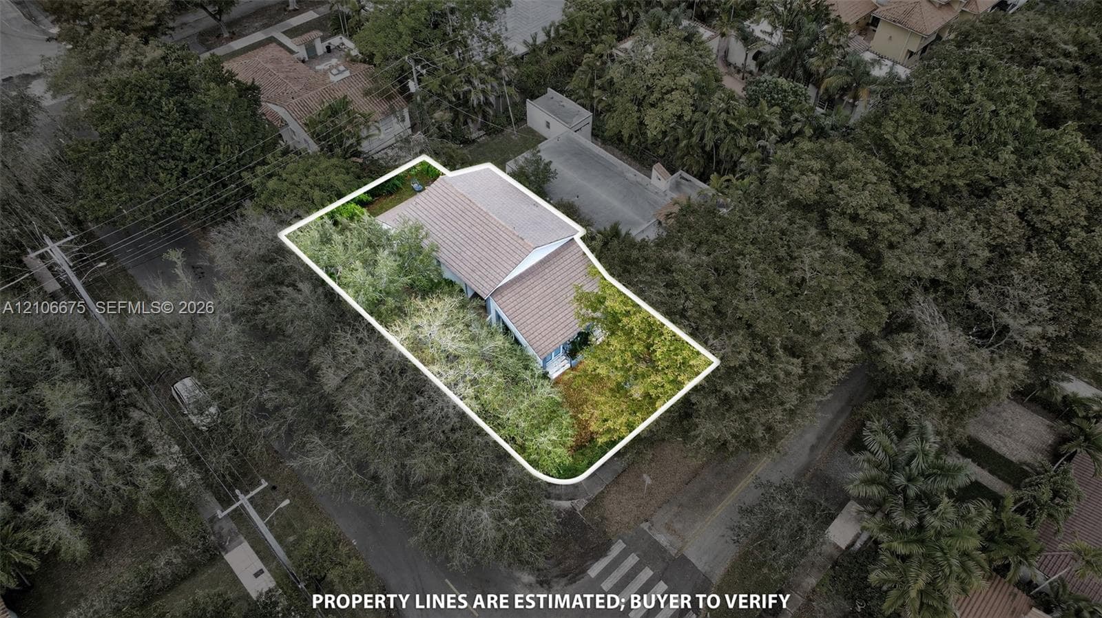 Aerial perspective of a detached residence featuring a multi-pitched tiled roof and a defined lot boundary situated within a heavily wooded landscape