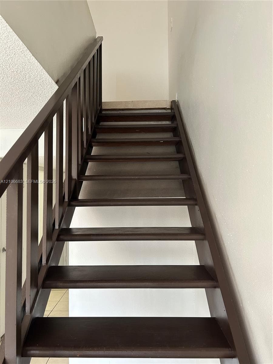 Open-riser staircase featuring stained wood treads and a matching dark wood railing