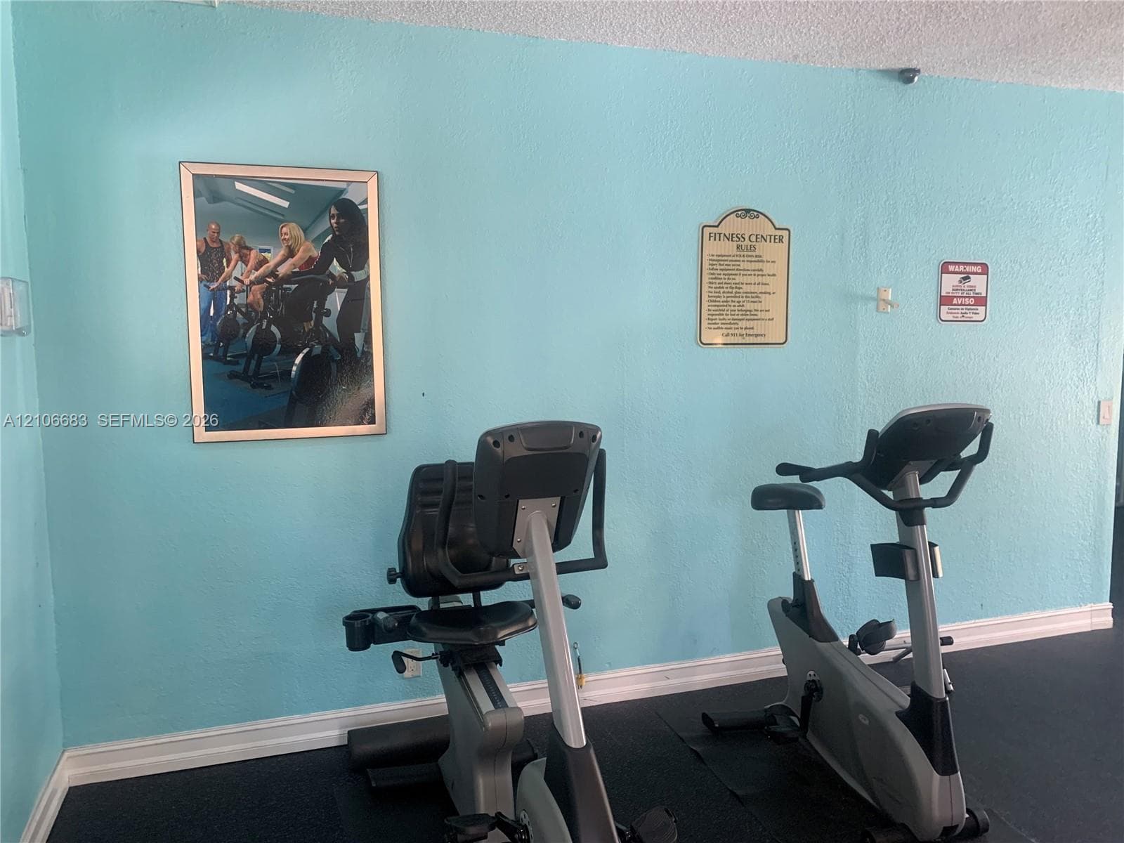 Fitness center featuring a textured wall finish and resilient flooring