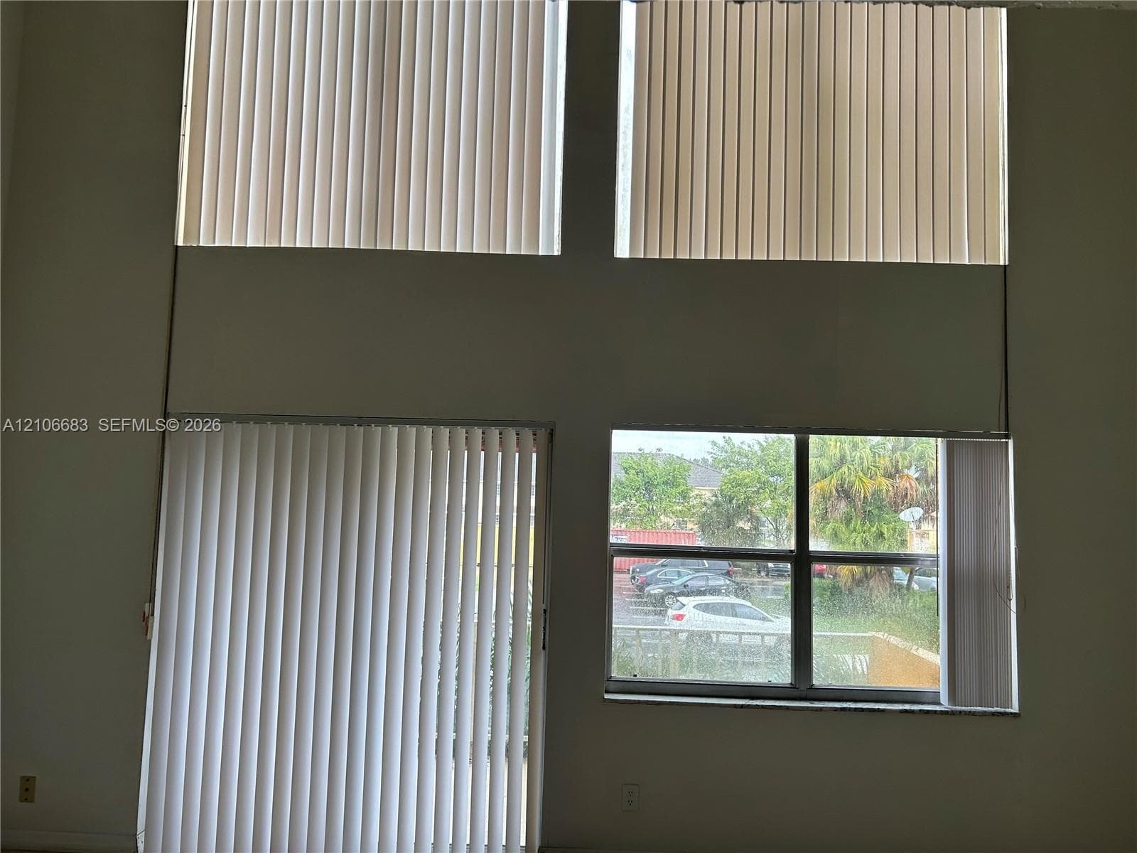 Double-height ceiling featuring floor-to-ceiling vertical blinds and expansive window arrays