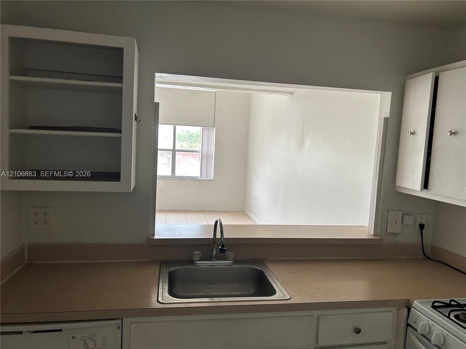 Kitchen featuring white cabinetry, solid-surface countertops, a stainless steel undermount sink with a gooseneck faucet, and an open pass-through window