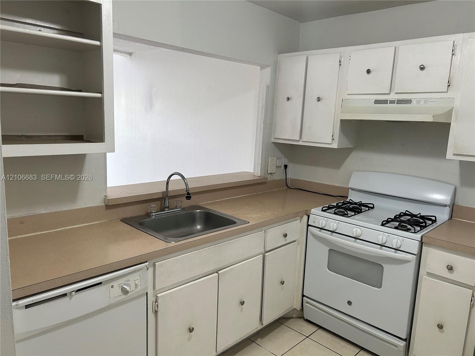 Kitchen featuring white cabinetry, solid-surface countertops, stainless steel sink with high-arch faucet, white dishwasher, and gas range