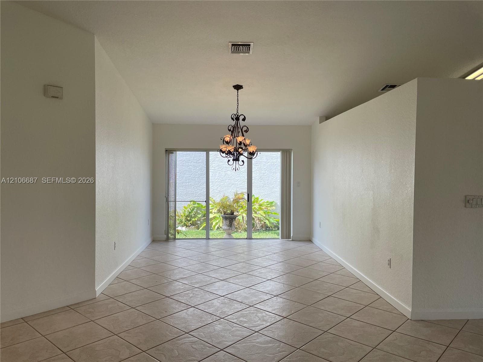 Interior space featuring diagonal ceramic tile flooring, a decorative metal chandelier, and floor-to-ceiling sliding glass doors