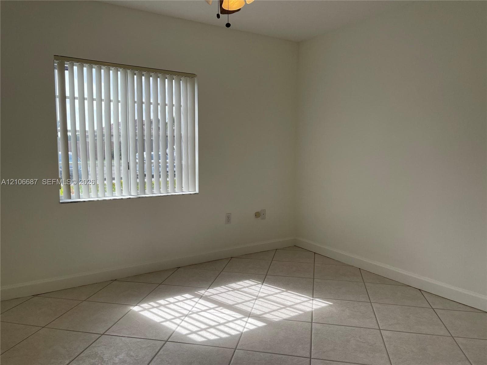 Neutral-toned tile flooring set on a diagonal pattern, vertical window blinds, and a ceiling-mounted light fixture