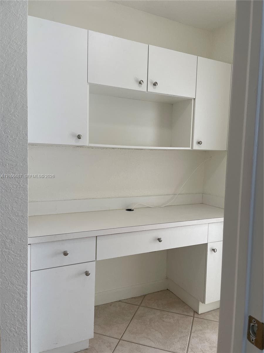 Bathroom featuring a white vanity with an integrated sink, a large wall-mounted mirror, a tiled shower surround, and a window with horizontal blinds