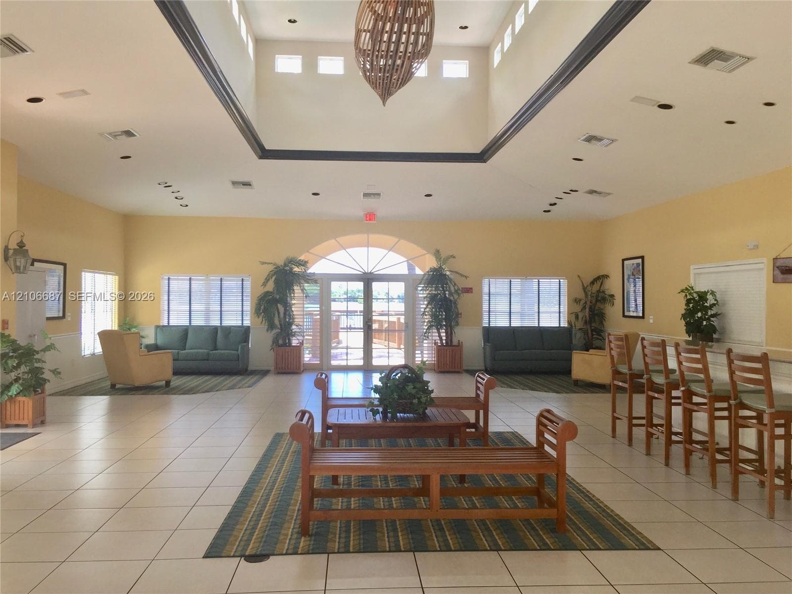 High-ceiling foyer featuring a central skylight, tile flooring, arched glass double-entry doors, and a built-in counter