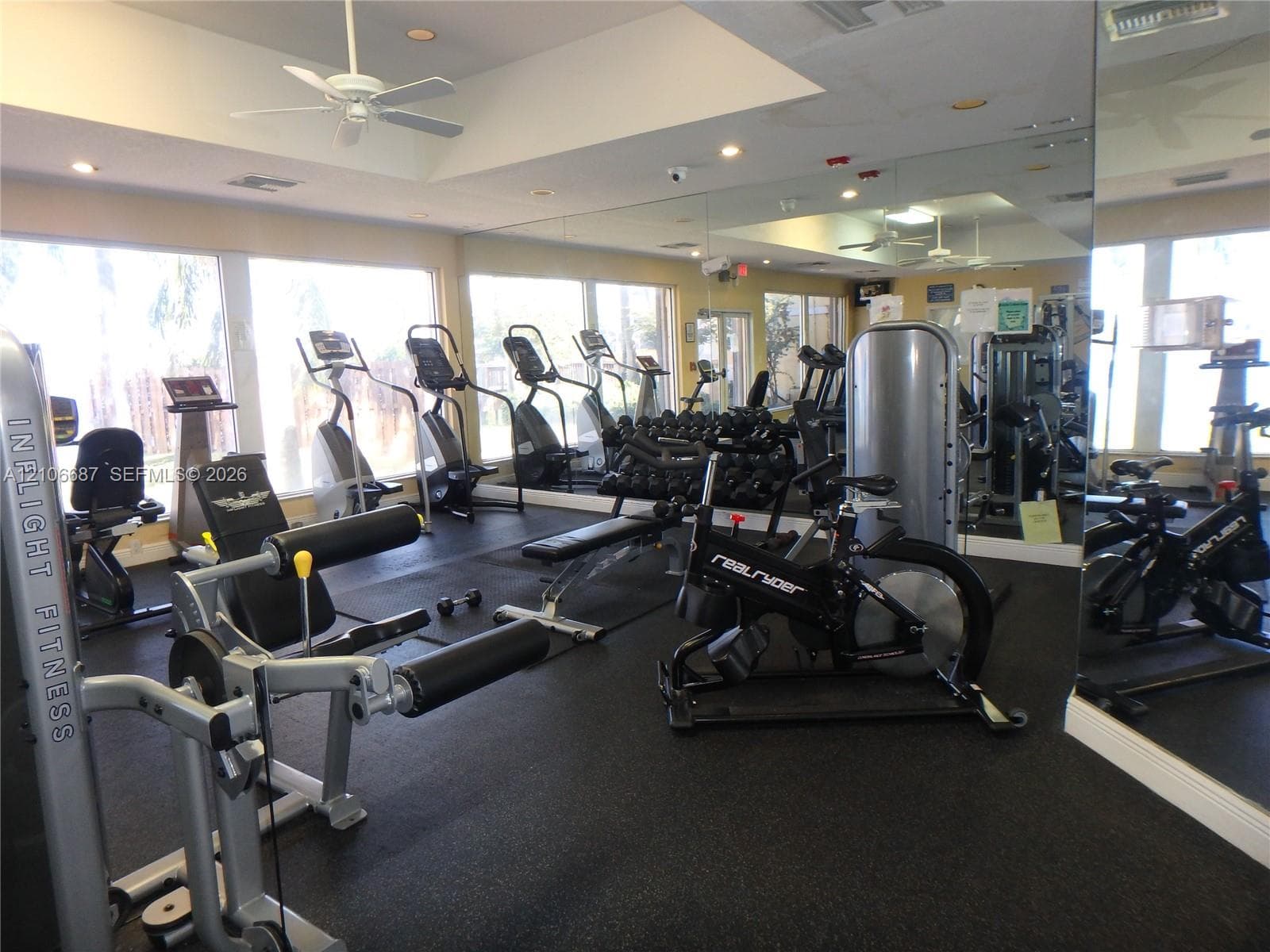 Fitness facility featuring wall-to-wall mirrors, recessed lighting, rubberized flooring, and floor-to-ceiling windows