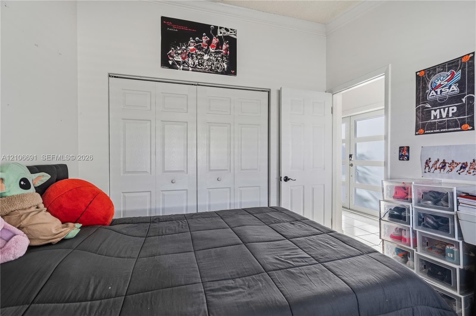 Interior room featuring neutral wall paint, white crown molding, dual-panel closet doors, and tile flooring