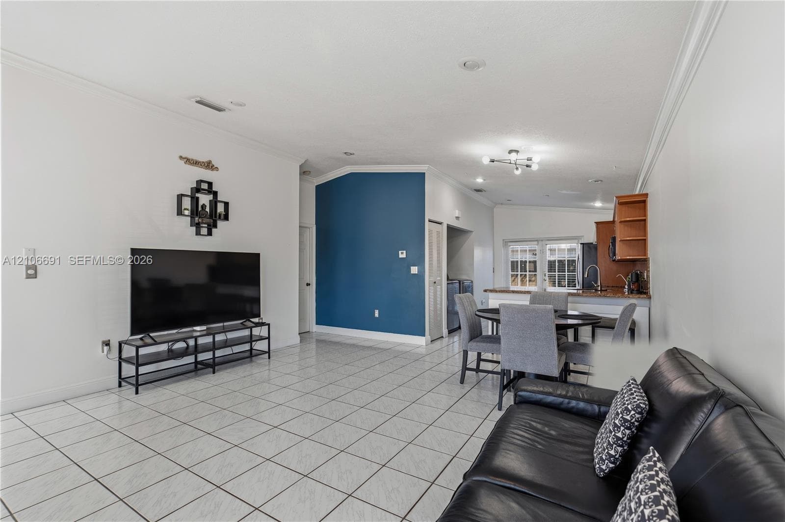 Open-concept interior featuring light-colored tile flooring, recessed lighting, and a prominent blue accent wall