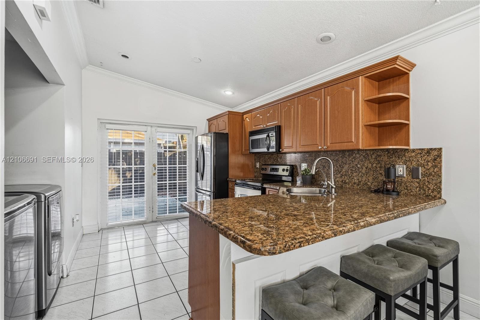 Kitchen featuring wood cabinetry, stone-surface countertops, tile flooring, recessed lighting, and dual glass-paned doors