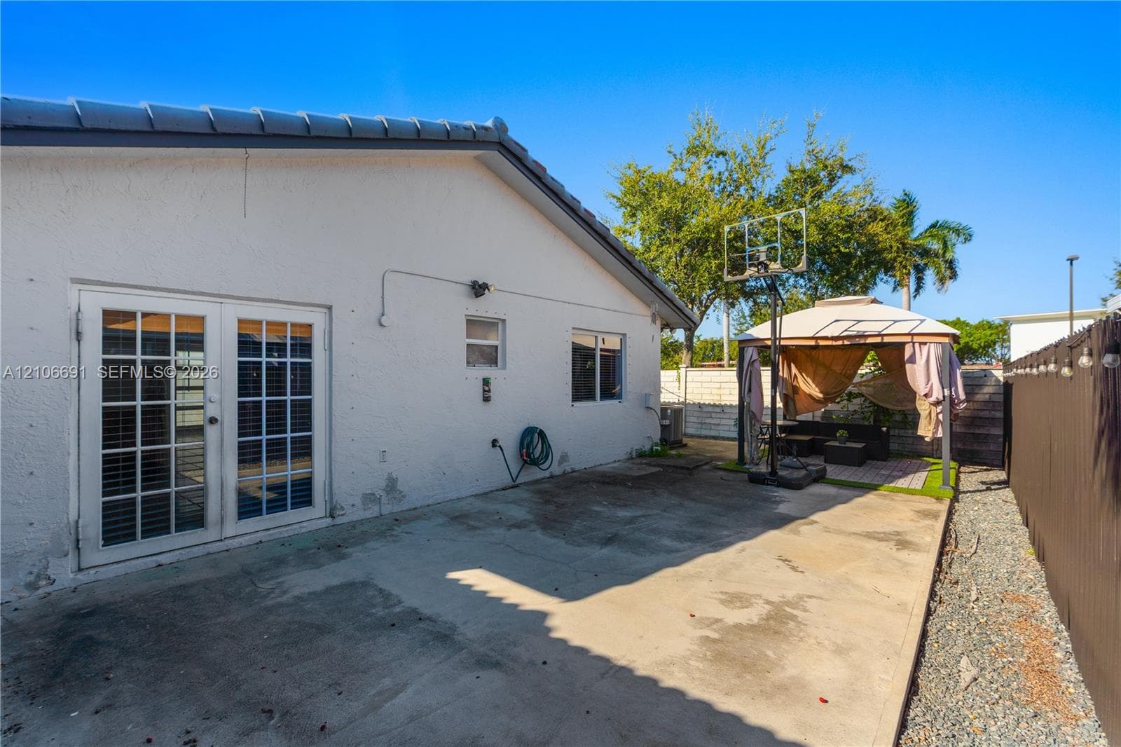 Exterior rear space featuring a concrete patio, double French doors, and perimeter fencing