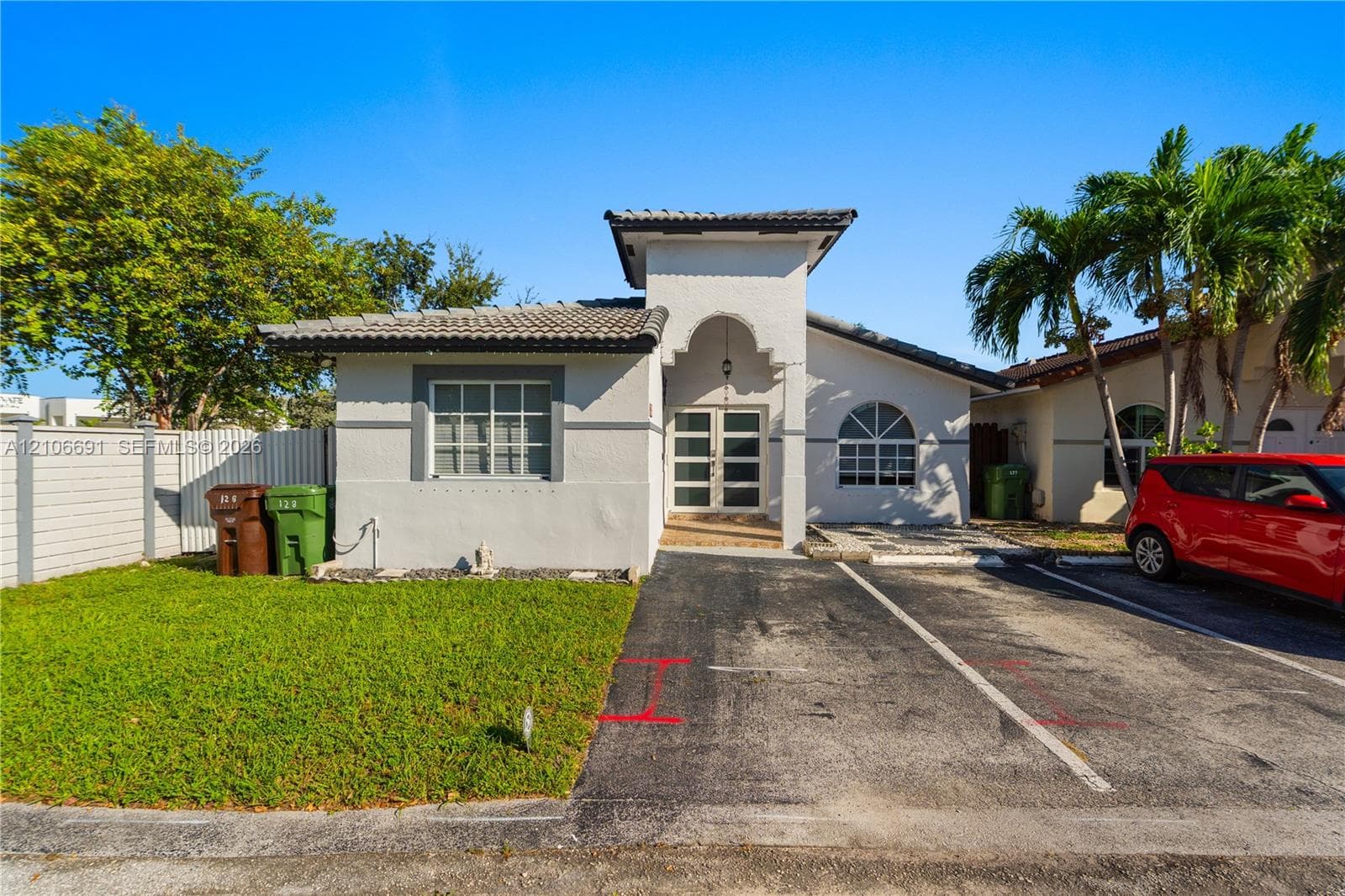 Stucco exterior featuring an arched entryway, double-glass front doors, tiled roof, and divided light windows