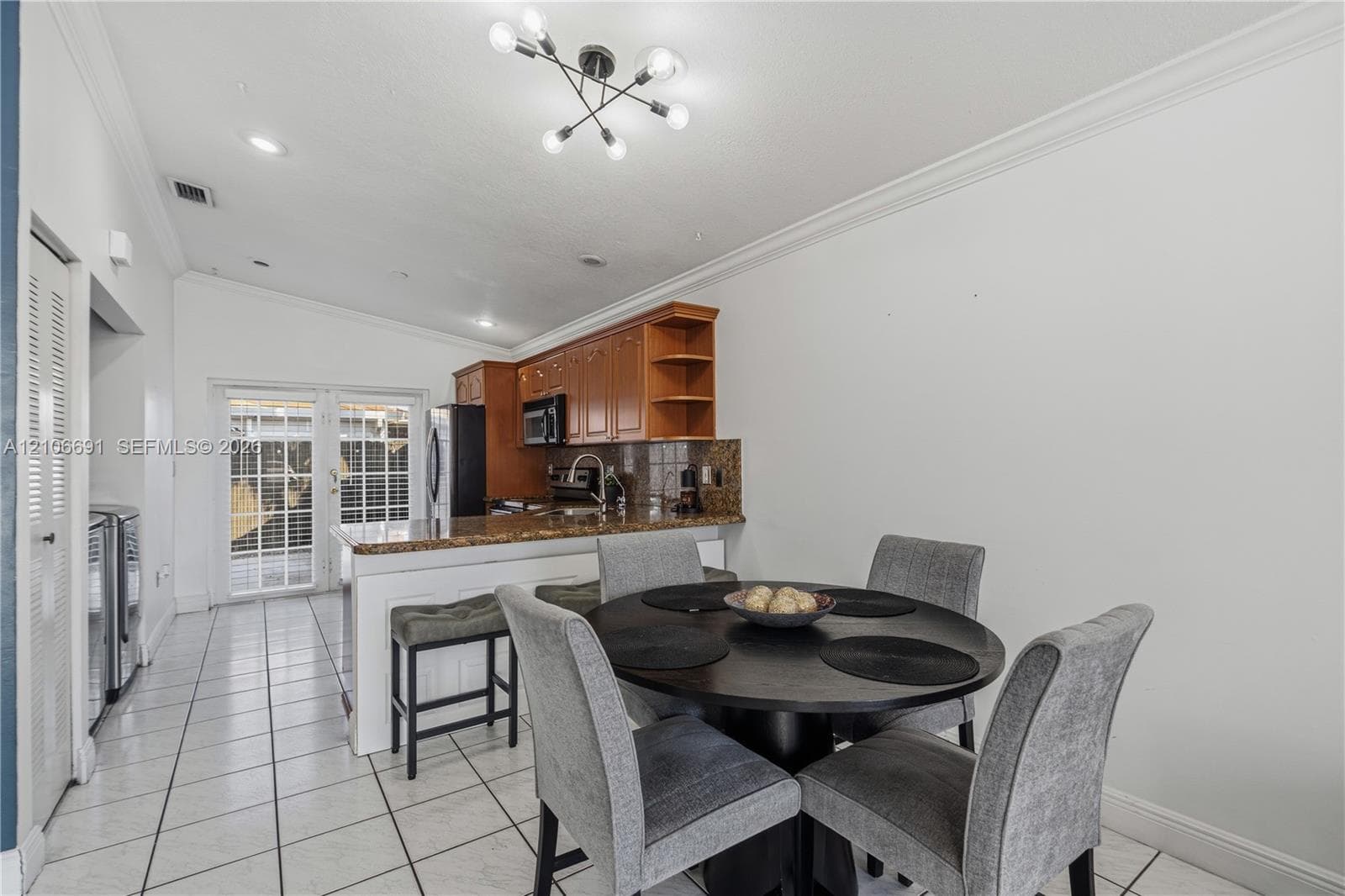 Kitchen featuring wood cabinetry, stone countertops, tiled flooring, vaulted ceilings, and glass-paned double doors