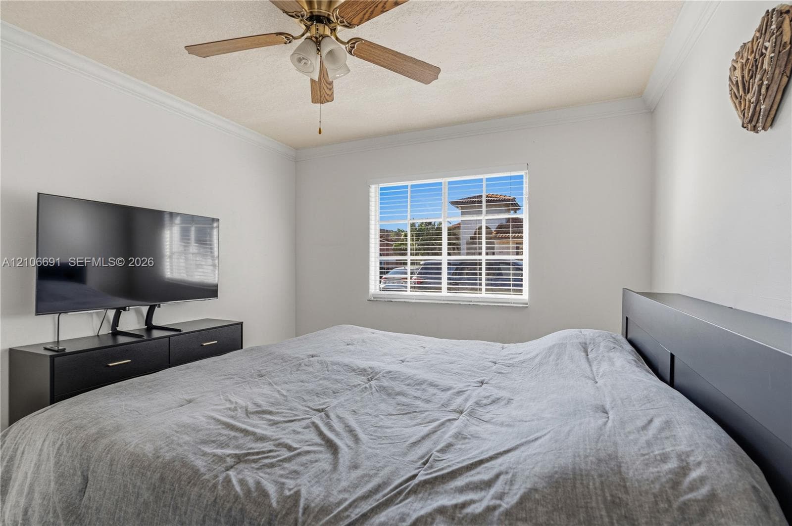 Multi-pane window with white frame, ceiling-mounted wooden blade fan with integrated light fixture, and crown molding