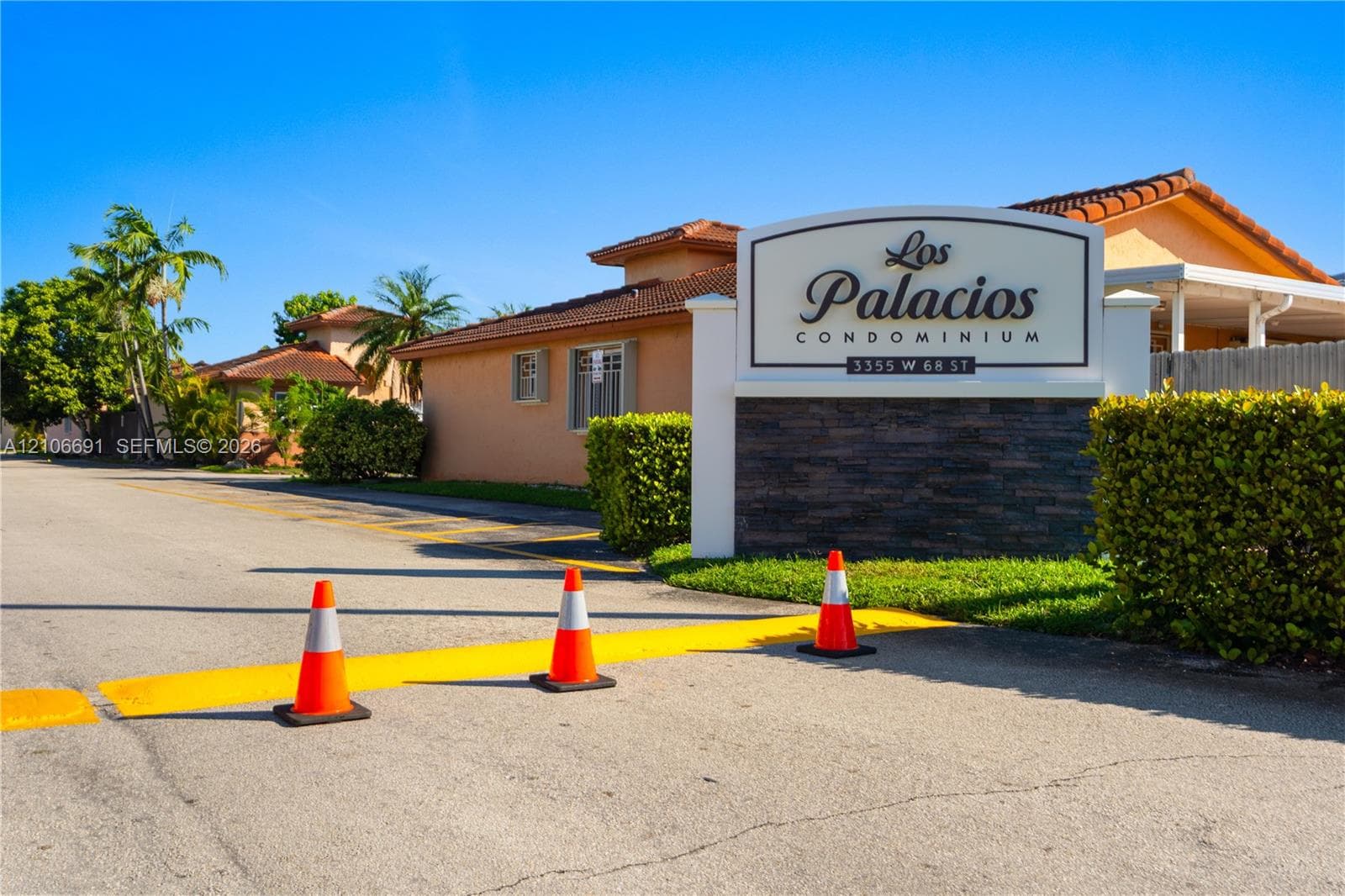 Los Palacios Condominium entrance featuring stucco-finished building exteriors, tile roofing, and a decorative stacked-stone monument sign