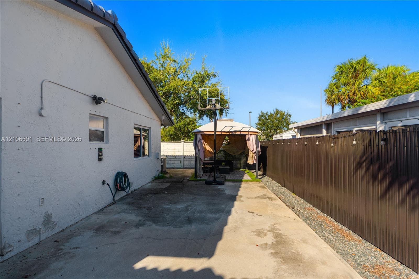 Concrete patio area featuring a metal privacy fence and white stucco exterior wall
