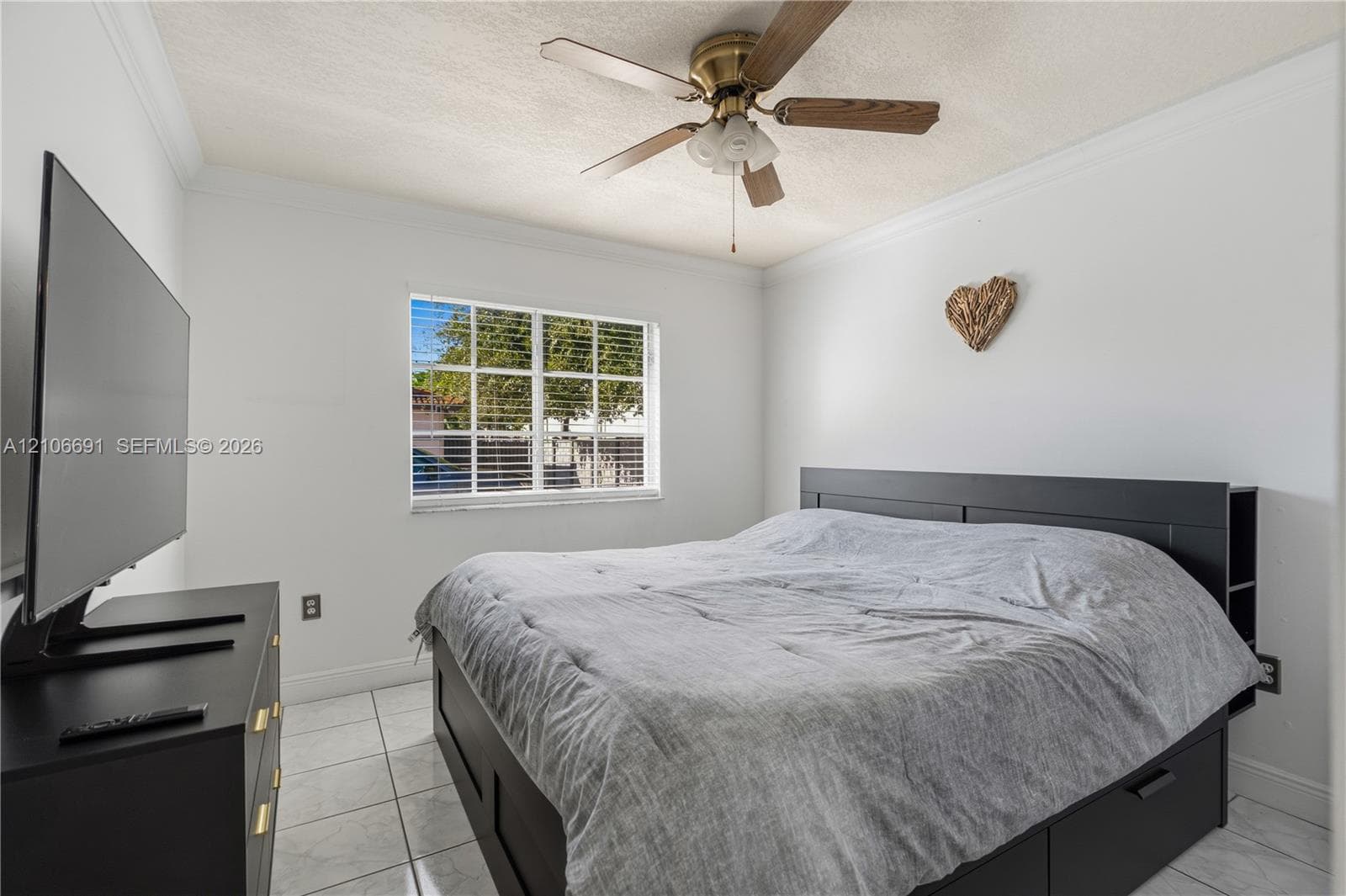 Neutral-toned room featuring a multi-pane window, tile flooring, and a ceiling-mounted fan with integrated lighting