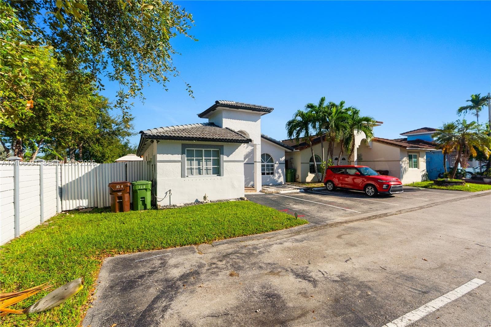 Stucco exterior featuring a tiled hip roof, arched window details, and paved surface parking