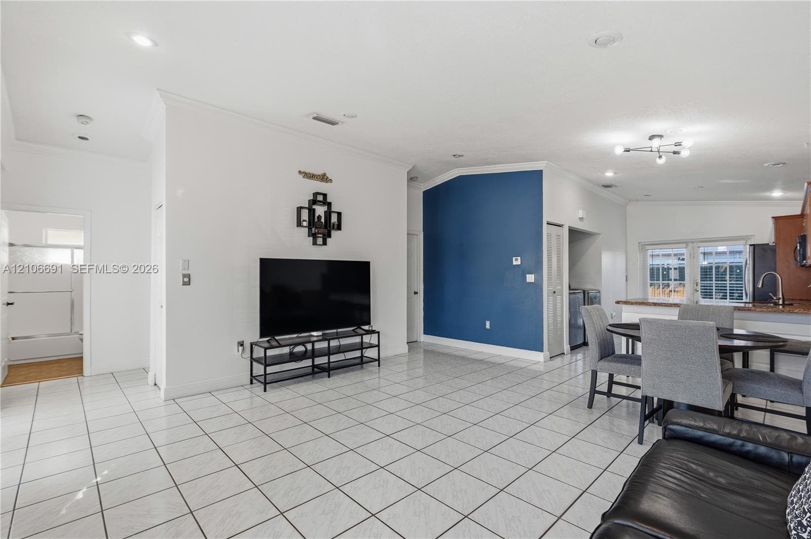 Open-concept interior featuring large-format ceramic tile flooring, vaulted ceilings, recessed lighting, and a distinct blue accent wall