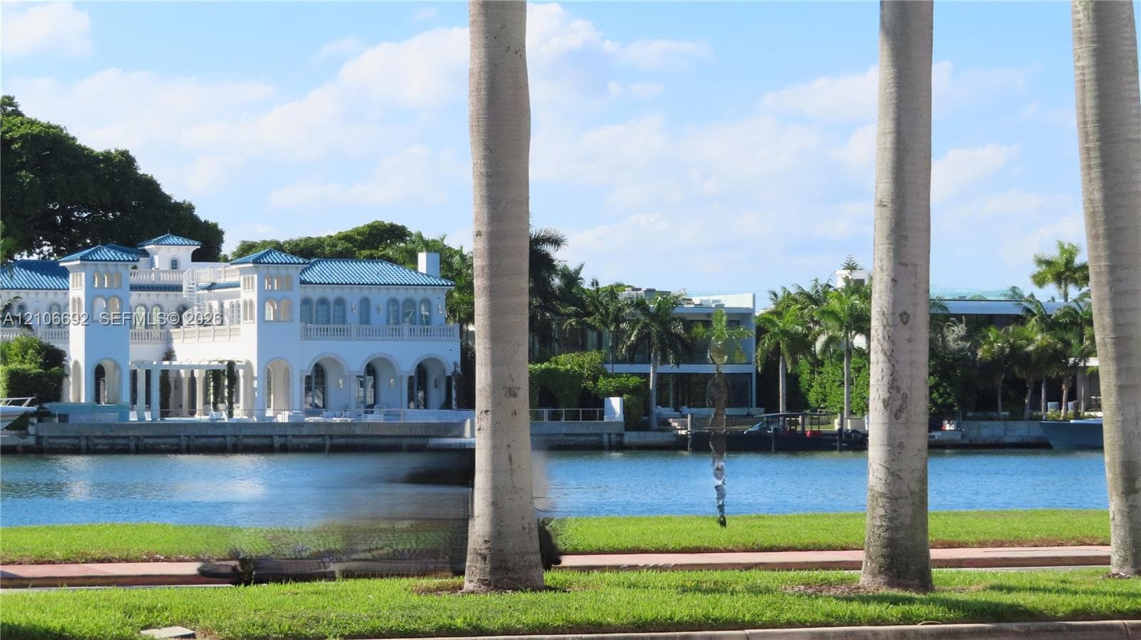 Waterfront estate featuring a Mediterranean-inspired architectural style, a blue tile roof, multiple archways, and a private bulkhead