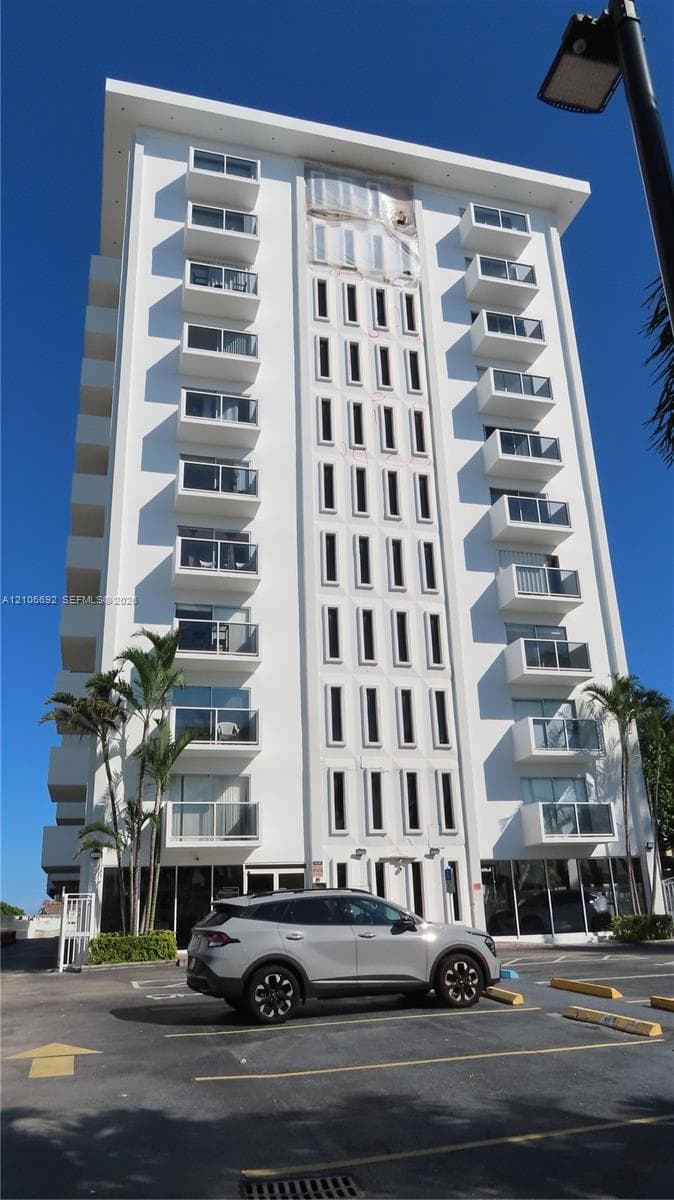 Multi-story high-rise exterior featuring a white facade, repeating glass-panel balconies, and vertical architectural detailing