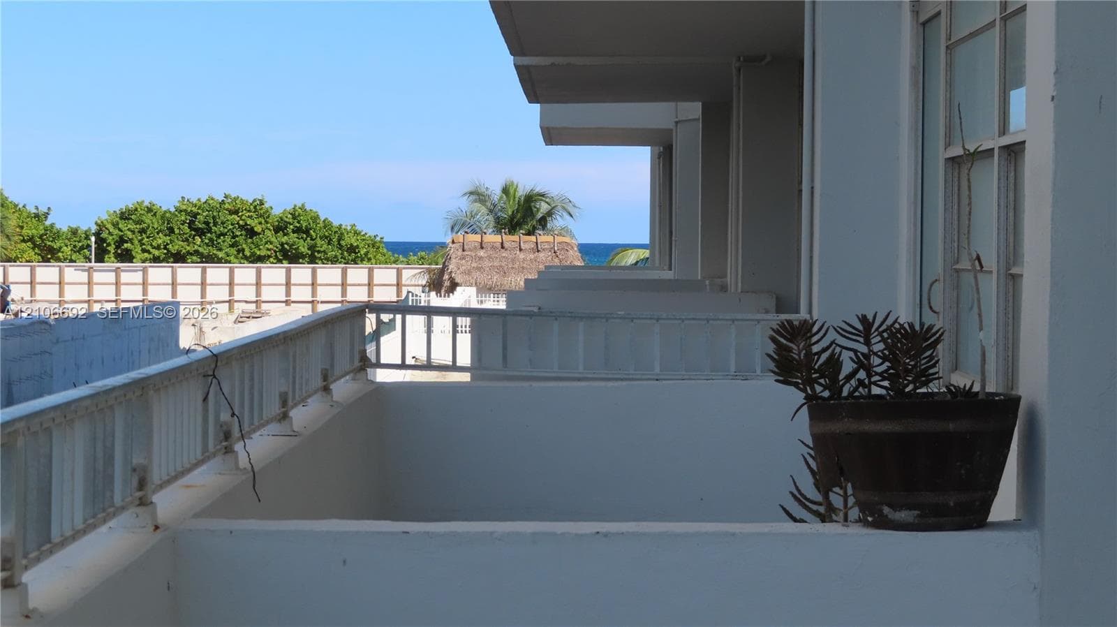 Private covered balcony featuring concrete partition walls and white metal railing