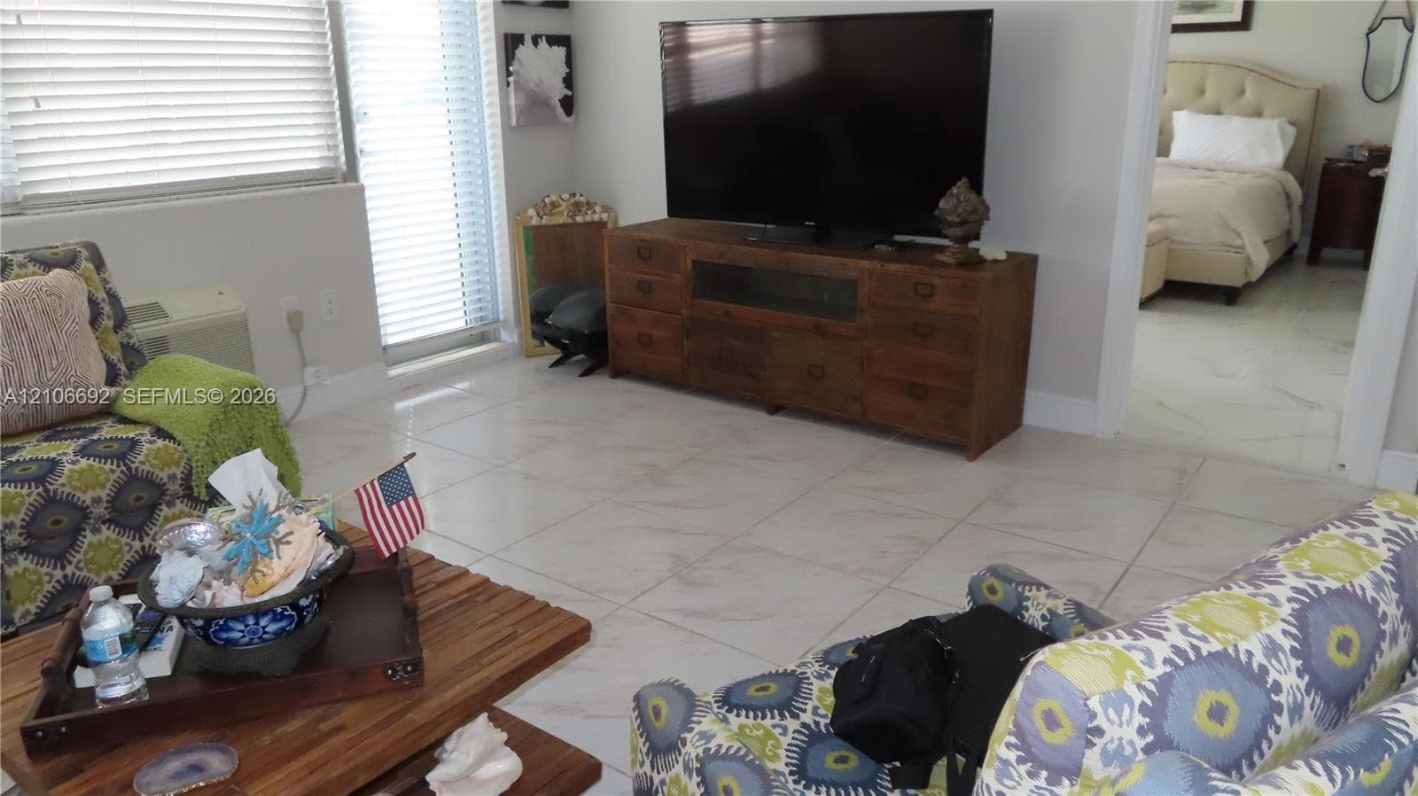 Living space featuring large-format tile flooring and horizontal window blinds
