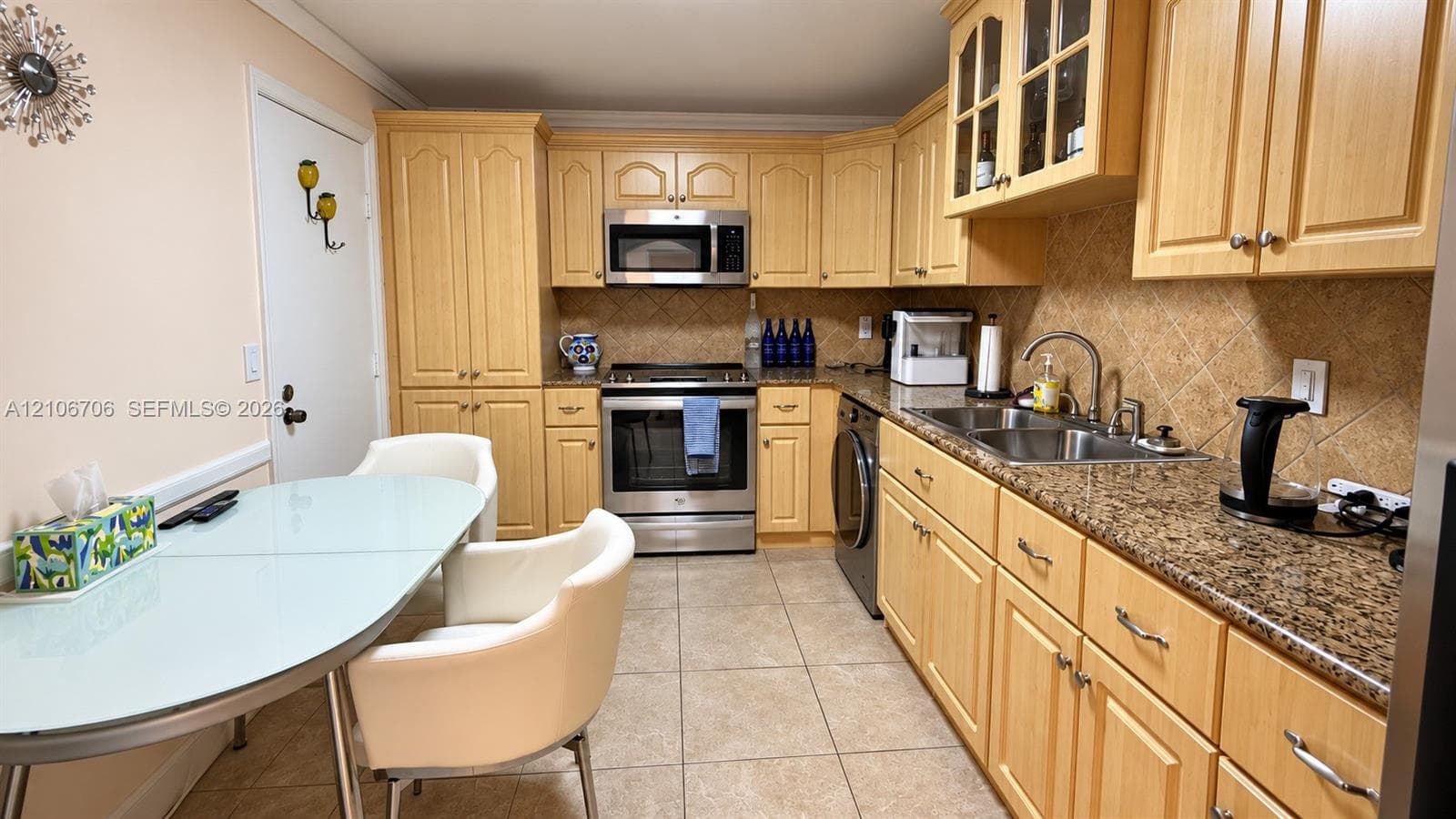 Kitchen featuring natural wood cabinetry, stone-finish countertops, stainless steel appliances, ceramic tile backsplash, and tile flooring