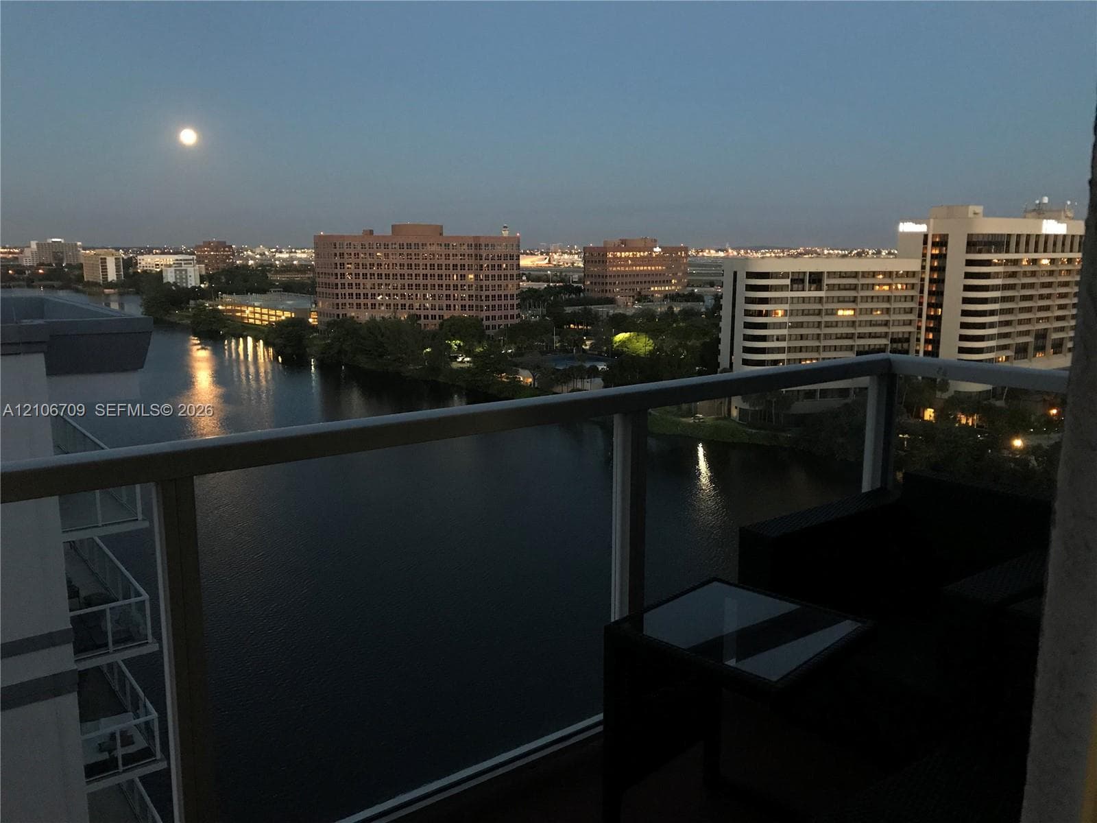 Private balcony with a metal and glass railing, overlooking an urban waterway