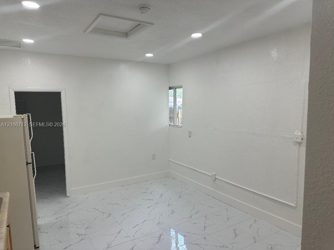 Interior space featuring white stone-finish floor tiles, recessed ceiling lighting, and smooth-finish walls