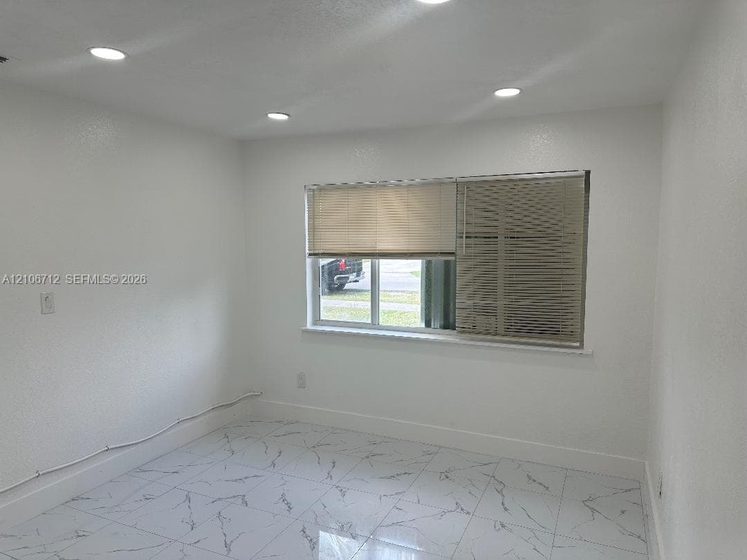 Neutral-toned interior featuring white-finish walls, polished tile flooring with a marble-style pattern, and recessed ceiling lighting