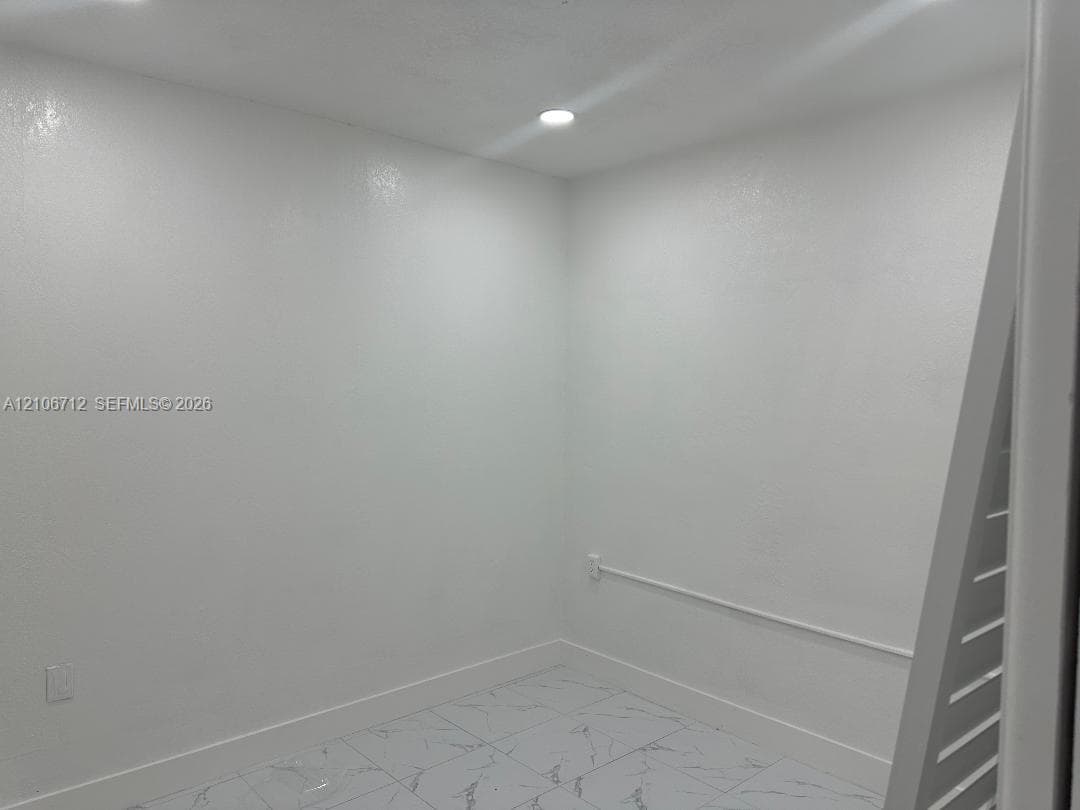 Interior space featuring neutral wall finishes, stone-style tile flooring, and integrated recessed lighting