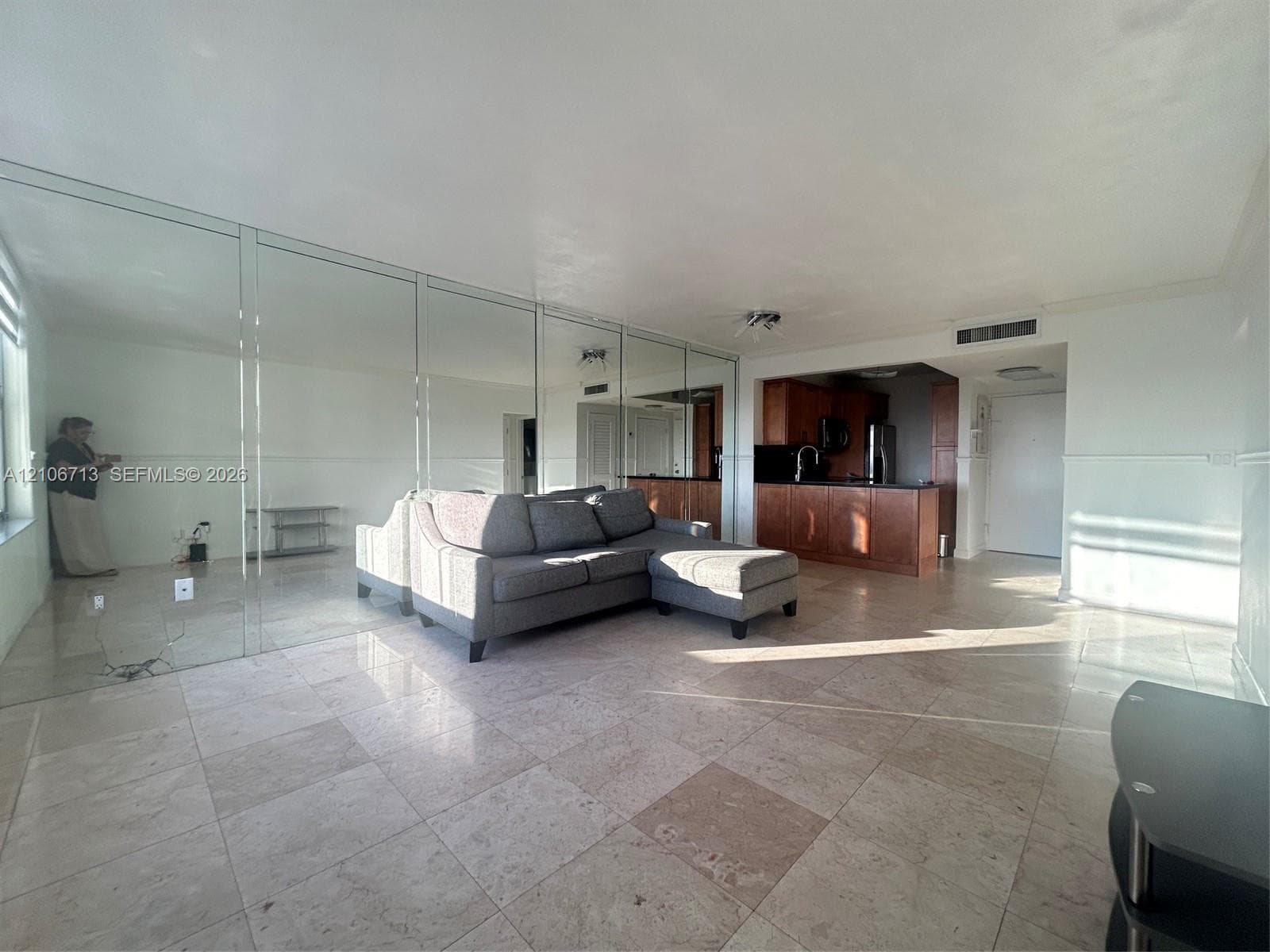 Large-format tile flooring, expansive mirrored wall, and built-in wood cabinetry with integrated countertops