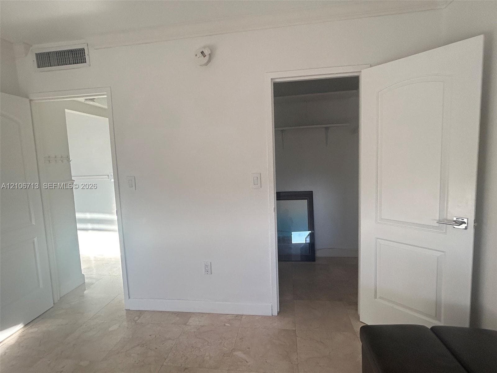 Room featuring stone tile flooring, two paneled interior doors, and a walk-in closet with built-in shelving