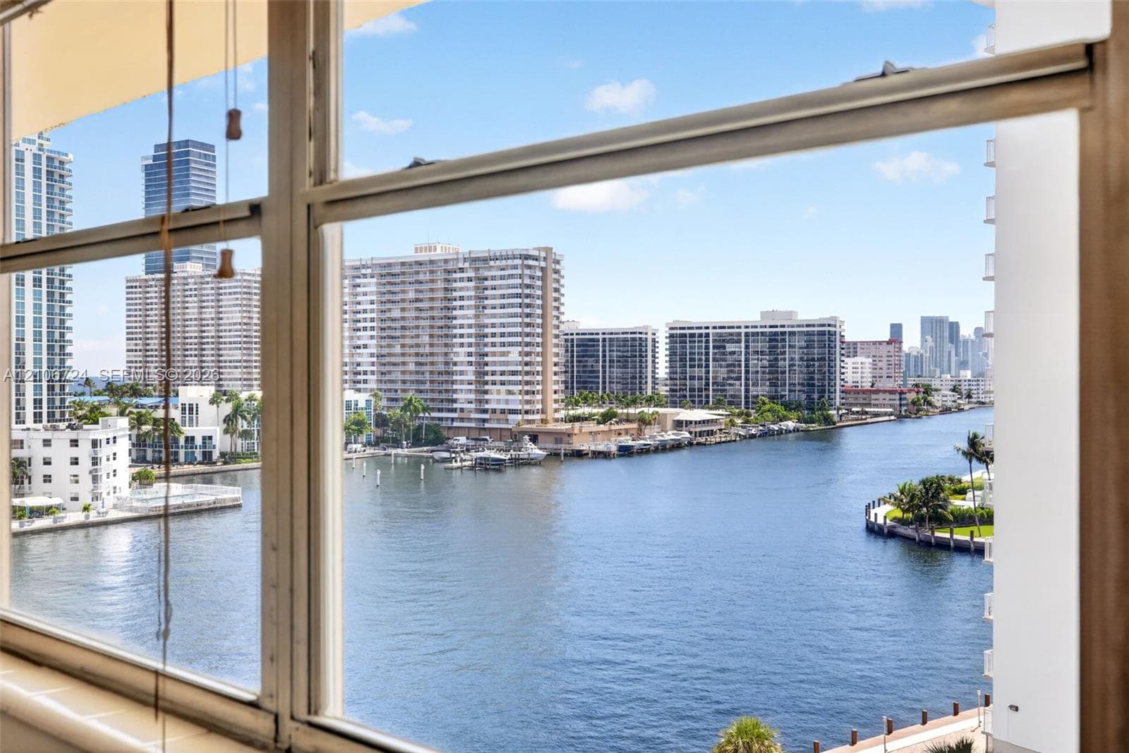 Panoramic water frontage and urban skyline backdrop framed by expansive metal-framed windows