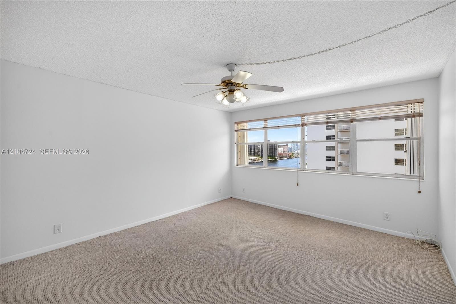 Neutral-toned carpeting, expansive horizontal windows, and a ceiling-mounted fan with integrated lighting