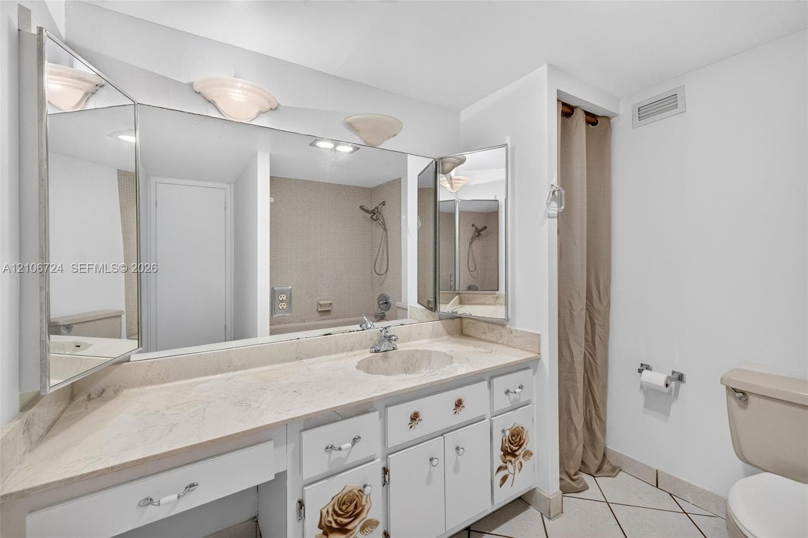Bathroom featuring a stone-surface vanity with an integrated basin, a large multi-panel mirror, ceramic tile flooring, and a combined tub and shower surround