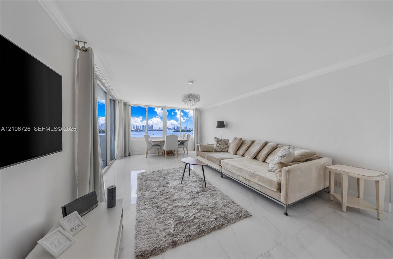 Open-concept living area featuring polished tile flooring, floor-to-ceiling windows, crown molding, and a drum-style ceiling light fixture