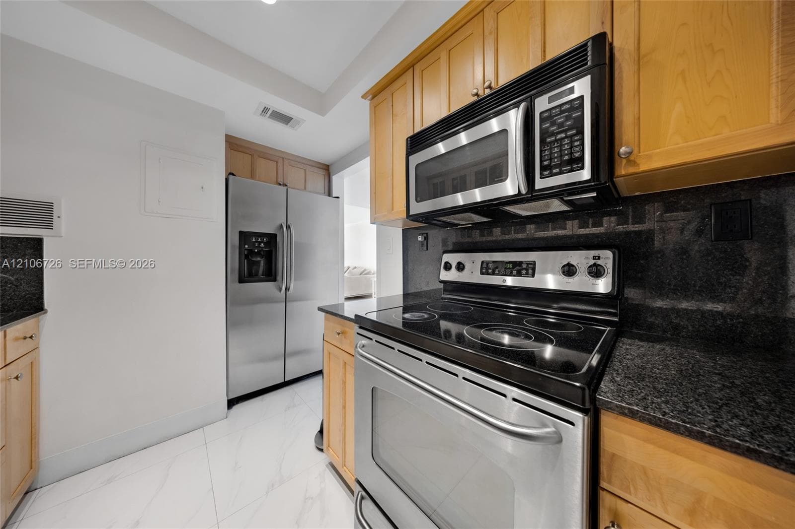 Kitchen featuring natural-finish wood cabinetry, stone countertops, stainless steel appliances, and tile flooring